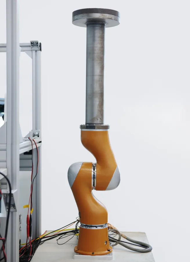Orange two-joint robot arm carrying a steel load on a test stand
